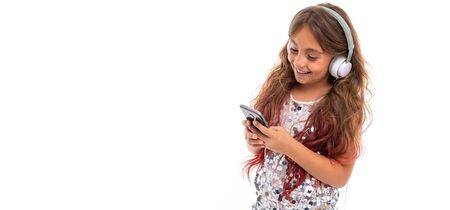 Panorama of girl in sparkling dress, with big white earphones listening to music and staring at...