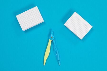Two stacks of white post-it and a compass in the middle on azure surface isolated