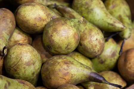 Close-up of green-brown pears on supermarket counter. Photo with depth of field