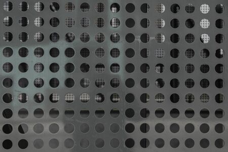 Closeup of gray metal surface with round holes