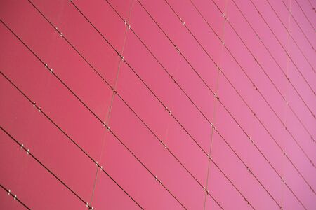 Ground view of red metal wall of a building made of small metal right angled sheets. Photo with...