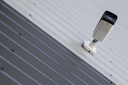 Bottom view of high-tech black and white video observation camera on black and white corrugated wall