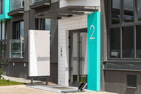 Mint-colored and grey entrance to house building with entryphone and empty advertisement tablet