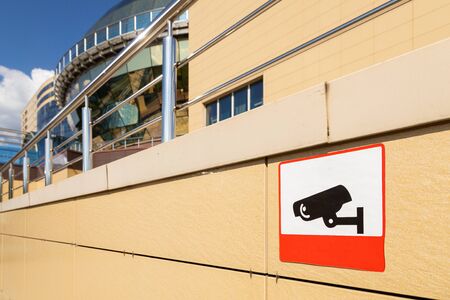 Close-up of sign informing about video monitoring area on beige building wall. Photo with depth of...