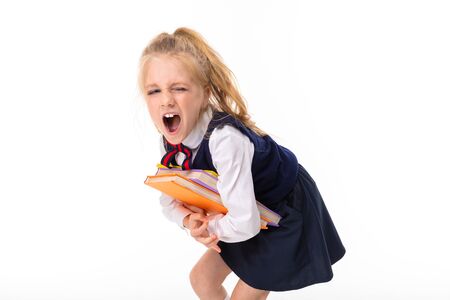 A little girl with blonde hair stuffed in a horse tail, large blue eyes and a cute face carries heavy books.の写真素材