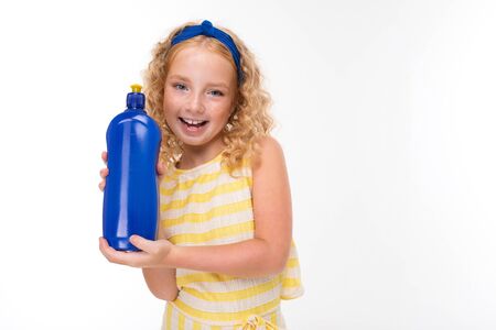 A little girl with red heap hair in a white and yellow striped summer suit, with a blue bandage on her head with a sponge and detergent.の写真素材