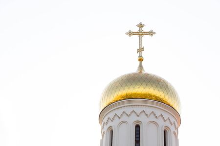 Close-up of shiny sunlit christian church dome with cross on top against sky