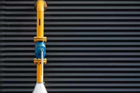 Close-up of yellow gas pipe against corrugated metal wallの写真素材