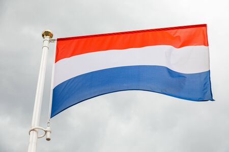 Dutch flag, on a flagstuff in front of the skyの写真素材