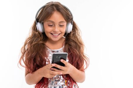 Happy girl holds phone in her hands with headphones on her head.