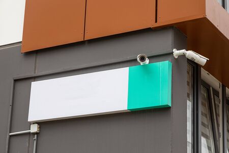 Two security cameras on new house building with white empty plateの写真素材