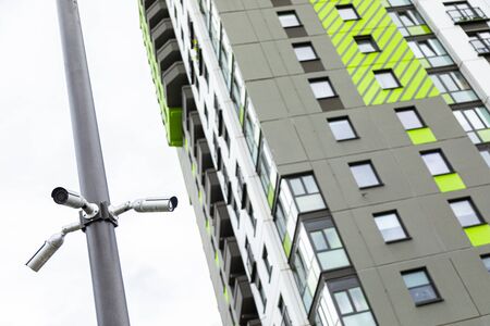 White surveillance cameras hanging on pile near new block of flats. Bottom viewの写真素材