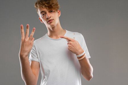handsome emotional teenager boy posing in studio against grayhandsome emotional teenager boy posing...