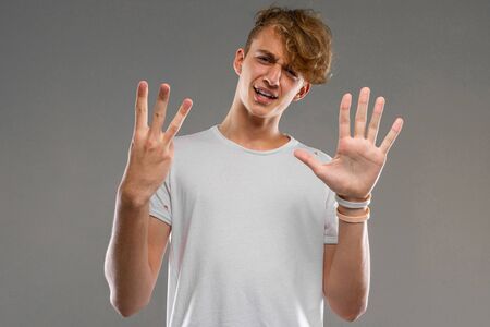 handsome emotional teenager boy posing in studio against gray