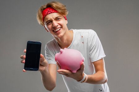teenager with piggy bank posing against gray