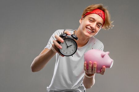 teenager with clock and piggy bank, prankster concept