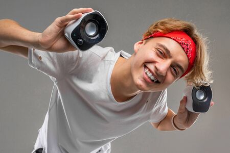 teenager with loudspeakers against gray, prankster concept