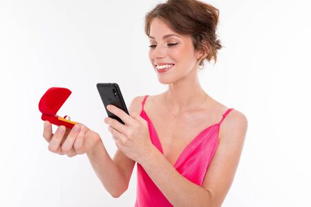 A young beautiful girl holds a training ring box and photographs it on her phone.