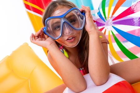 Girl with long crucified hair in sunglasses and swimsuit sits on inflatable mattresses with goggles.の写真素材