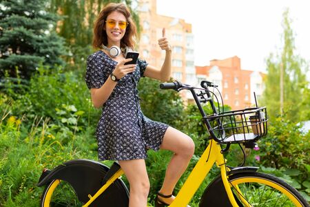 young caucasian woman with perfect smile, plump lips, glasses, earphones, walks in nature, ride a...