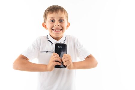 happy boy with a phone in his hands smiling with teeth, photograph of a child on a white isolated backgroundの写真素材