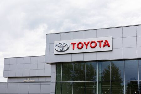 Minsk, Belarus - July 15, 2019: Toyota logo and signature on gray tiles building with dark windows on gray cloudy sky background. Toyota is a Japanese Automaker Headquartered in Toyota, Aichi, Japanのeditorial素材