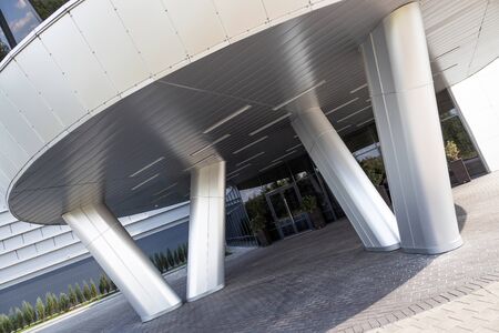Angular view of modern unusual entrance to building under awning with inclined metal columns