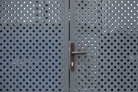 Closeup metal gates with round holes and iron handleの写真素材