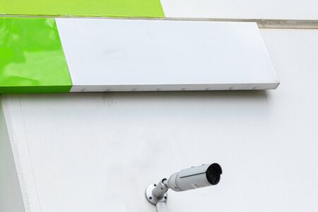 White surveillance videocamera on white wall with empty tablet above itの写真素材