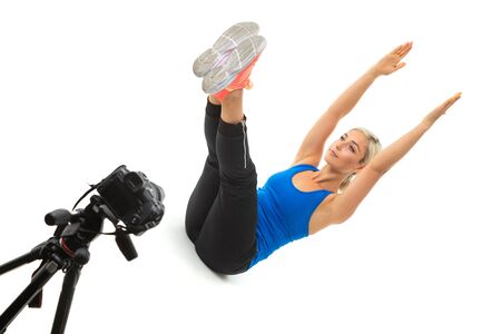 The young sporty girl with a fair hair sits in front of the camera and shows how to do exercise.の写真素材