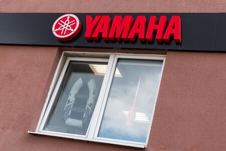 Minsk, Belarus - July 16, 2019: red Yamaha logo on black background, brand board on bulding beyong...