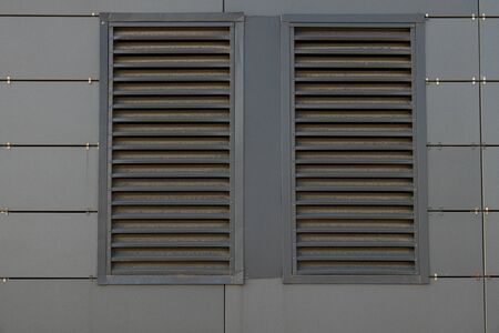 Front view of dusty dark grey transfer grill in dark grey metal wall