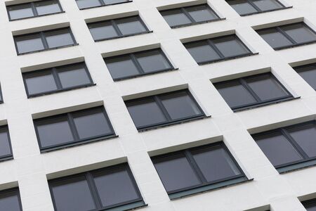 New apartment facade painted white smooth parget and dark black windows, diagonal view, ground viewの写真素材