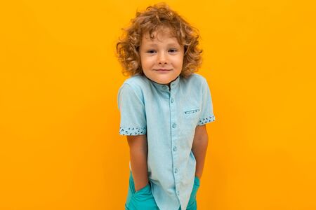 European red-haired boy in a light blue T-shirt on a yellow background.