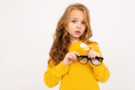young girl holding a container for lenses and glasses in his hand on a white studio background.の写真素材