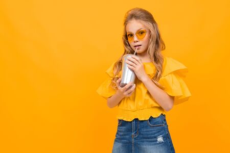Nice little girl with her glasses drinks a coctail and smiles isolated on white background.の写真素材