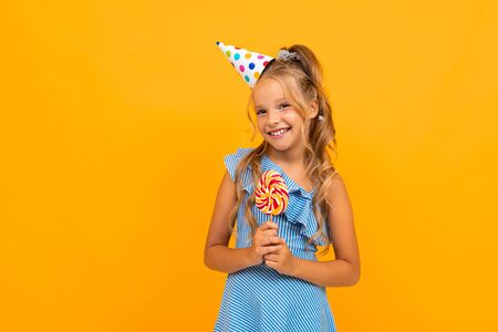 girl at a party with candy on a yellow background with copy space.
