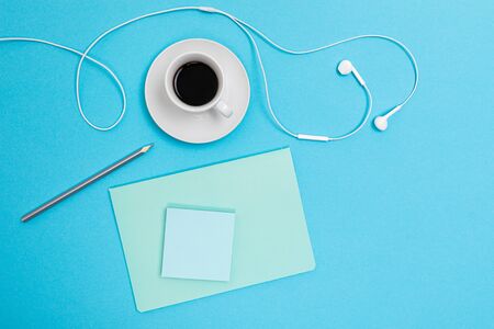 School and office supplies such as note, pens, pencils, calculator, brush, scissors, coffee, laptop lie neatly on a white and blue backgroundの写真素材