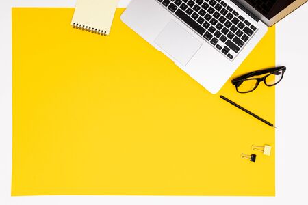 School and office supplies such as note, pens, pencils and other lie neatly on a yellow backgroundの写真素材