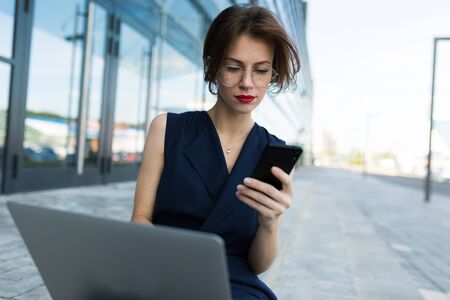 Pretty caucasian female in office clothes do freelance with laptop near the office building and...