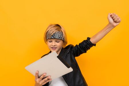 European boy with a tablet on an orange background.