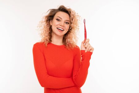 portrait of a cute curly european girl holding a toothbrush in hands on a white isolated background.の写真素材