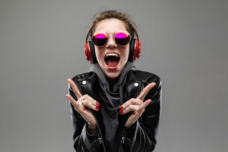 smiling impudent girl listens to music in red headphones on a gray background.の写真素材