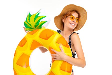 lovely girl in glasses and a straw hat with a swimming circle in the shape of pineapple on a white background.の写真素材