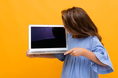 girl looking at laptop display with mockup on yellow background.の写真素材