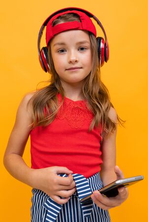 portrait of a cute charming young girl with red headphones on a yellow background.の写真素材