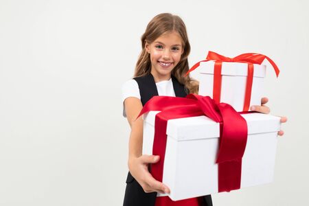 Beautiful caucasian girl in black jacket, white shirt and red pants holds a white boxes with gifts and rejoices isolated on whiteの写真素材