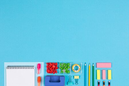 Notes, pens, pencils, ruler, eraser, compass isolated on blue background