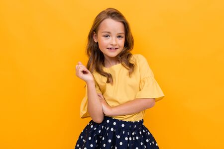 stylish charming young girl in a light yellow blouse and skirt on a yellow background.の写真素材