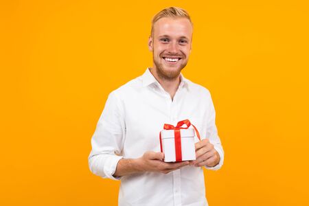 Caucasian blond with a gift for Valentines Day on a yellow background.の写真素材